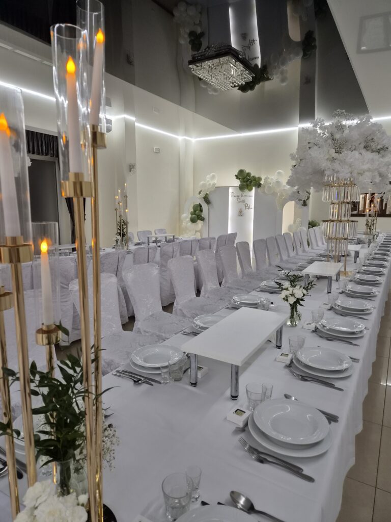 Elegancka dekoracja stołu komunijnego z wysokimi kompozycjami kwiatowymi